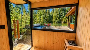 A wooden interior with a large window overlooking a lake and forest.