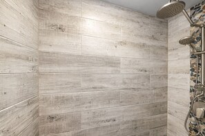 A shower area with wooden panel walls and a mosaic tile accent.