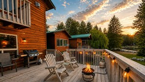 Eine Holzterrasse mit Sitzgelegenheit, Grill und Feuerstelle.