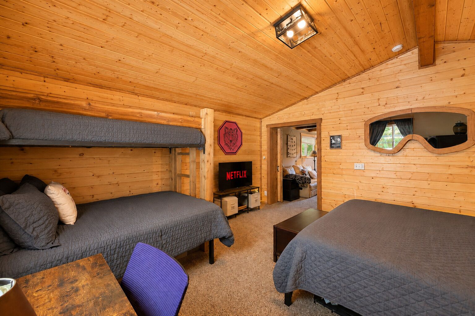 Una cabaña de madera con dos literas, un televisor y una mesita.