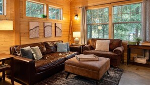 Ein gemütliches Blockhaus-Interieur mit Ledersofas, einem Couchtisch und Kunstwerken an den Wänden.