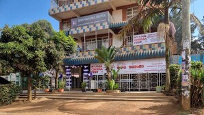Hotel con fachada a cuadros, cartel del Festival Nyama Choma y un camino de tierra en primer plano.
