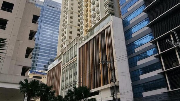 A modern high-rise building with a mix of glass and wood facade, surrounded by other tall buildings.