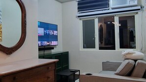 A living room with a TV, a dresser, a sofa, and a window with blinds.