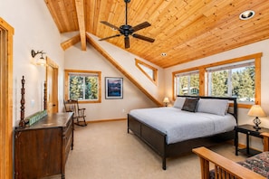 A bedroom with a bed, a desk, a chair, a ceiling fan, and windows with a view of trees. - Peterson Acres 3 Bedroom Home by NW Comfy Cabins by RedAwning (Leavenworth)