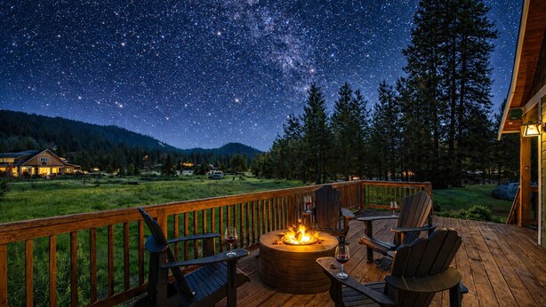 A deck with a fire pit, chairs, and a view of the night sky.