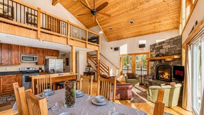 A spacious living area with a fireplace, a dining table set for four, and a kitchen with modern appliances.
