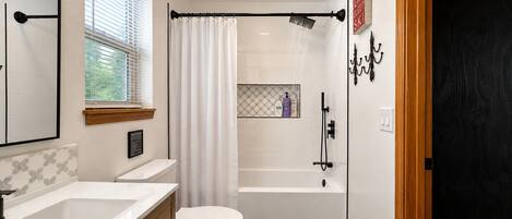 Een moderne badkamer met douche, toilet en wastafel.