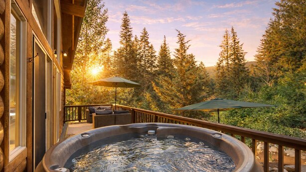 A hot tub on a wooden deck with a view of a forest and a sunset. - Raven Haven Lodge 2 Bedroom Home by RedAwning (Leavenworth)