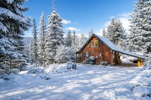 Une cabane en bois entourée d’arbres couverts de neige.