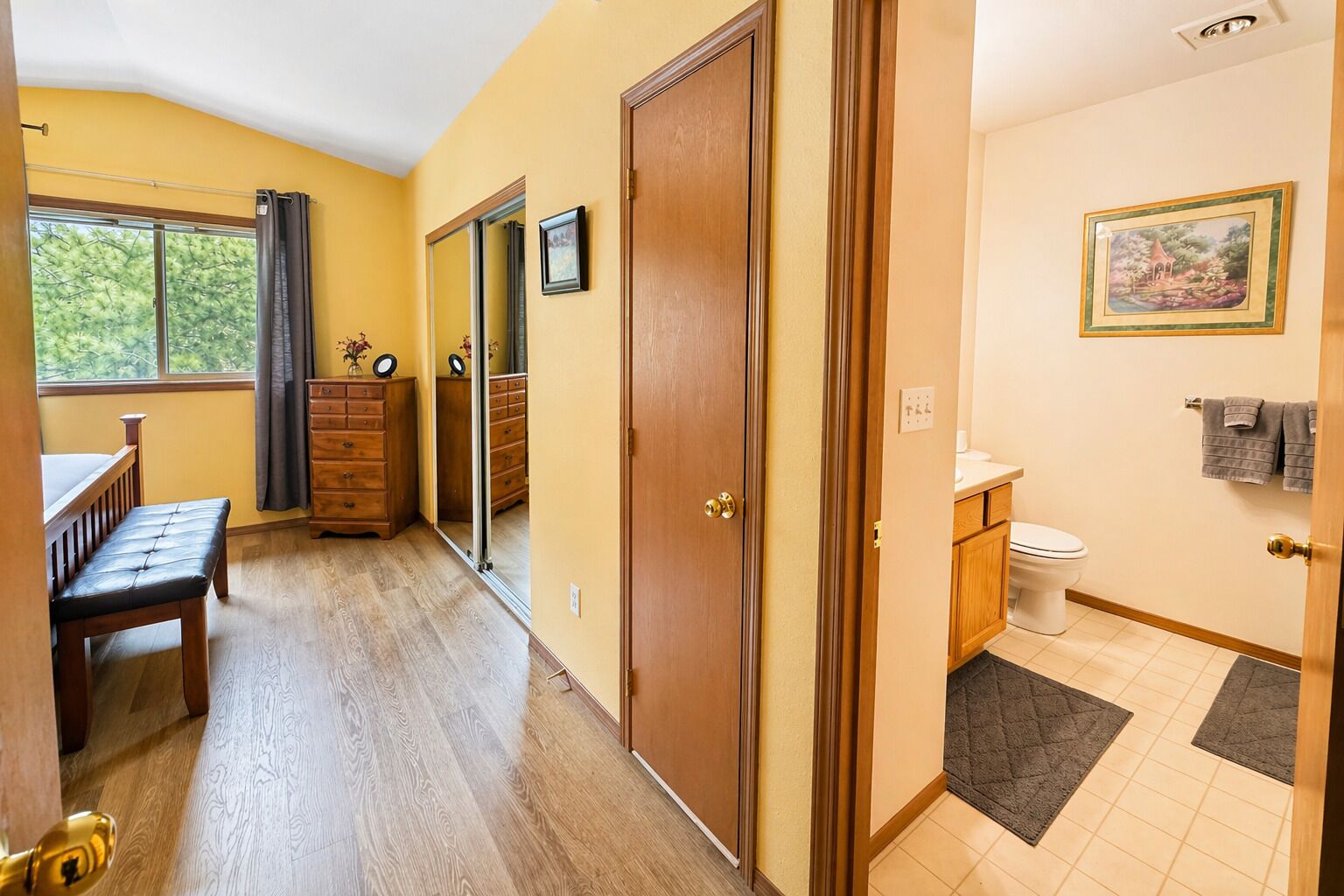 Una habitación con un banco de madera, un aparador, una puerta y vistas al exterior a través de una ventana.