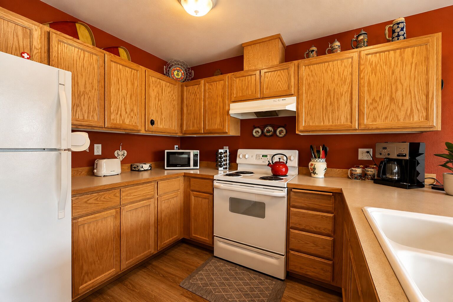A kitchen with wooden cabinets, a white refrigerator, a microwave, a stove, and a coffee maker.
