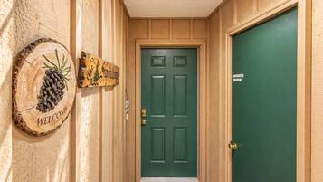 A wooden hallway with a green door, a welcome sign, and a sign indicating a private room.