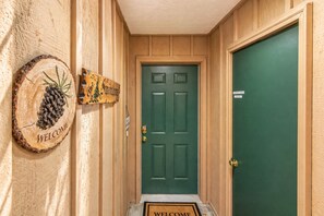A wooden hallway with a green door, a welcome sign, and a sign indicating a private room. - Suite Serenity 3 Bedroom Condo by NW Comfy Cabins by RedAwning (Leavenworth)