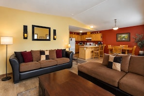 A living room with a sofa, a coffee table, and a dining area with chairs and a table.
