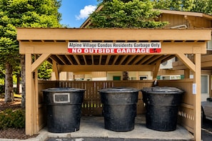 A wooden structure with a sign indicating it's for Alpine Village Condos residents' garbage only, with three black trash bins underneath. - Suite Serenity 3 Bedroom Condo by NW Comfy Cabins by RedAwning (Leavenworth)