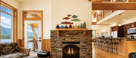 A cozy living room with a stone fireplace, wooden furniture, and a view of a lake.