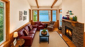 Un salon chaleureux avec une cheminée, un canapé en cuir et une vue sur un lac.