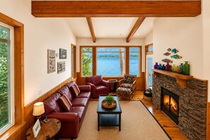 Una sala de estar acogedora con chimenea, sofá de cuero y vistas a un lago.