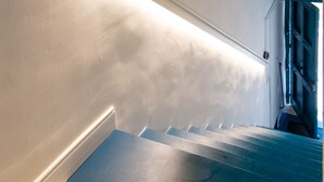 A staircase with a patterned floor and a light fixture along the wall. - Relais Metis (Naples)