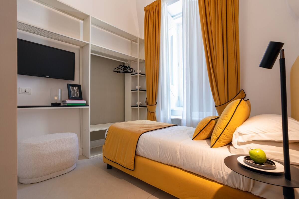 Une chambre à coucher avec un lit, une table de chevet, une télévision et une armoire.