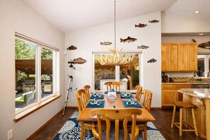 Un coin repas avec une table et des chaises en bois, un lustre et des œuvres d’art murales représentant des poissons.