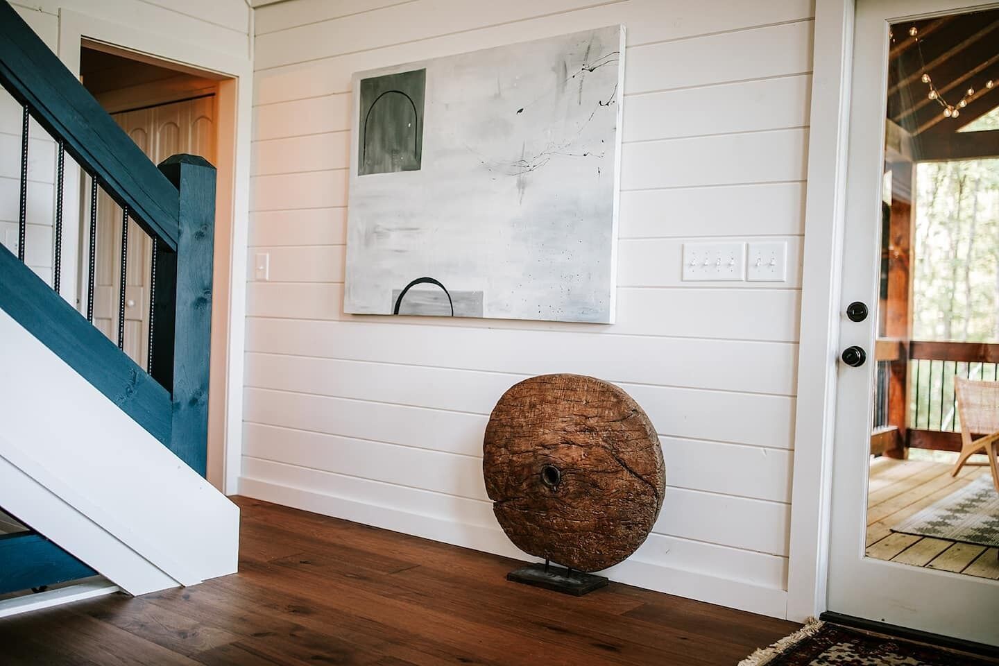 Un piso de madera, una puerta blanca y una escalera con detalles azules.