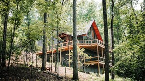 Eine Holzhütte mit rotem Dach, auf Stelzen in einem bewaldeten Gebiet gebaut.