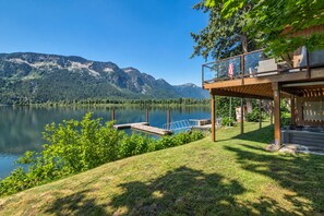 Una propiedad frente al lago con una terraza de madera, un jacuzzi y vistas a las montañas.