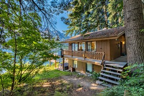 A wooden cabin with a deck, overlooking a lake and surrounded by trees. - All About The Lake 4 Bedroom Home by NW Comfy Cabins by RedAwning (Leavenworth)