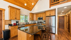 A spacious kitchen with wooden cabinets, a large island, stainless steel appliances, and a view of the outdoors. - Getaway Moose 3 Bedroom Home by NW Comfy Cabins by RedAwning (Leavenworth)