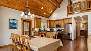 A spacious kitchen with wooden cabinets, a dining table, and a chandelier. - Getaway Moose 3 Bedroom Home by NW Comfy Cabins by RedAwning (Leavenworth)