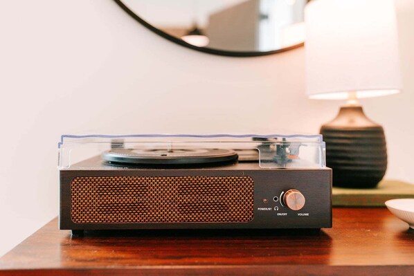A vintage turntable on a wooden table with a lamp in the background.