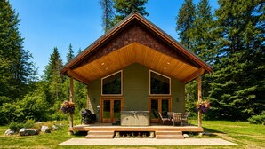A cabin with a porch, outdoor grill, and hot tub.