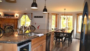 Eine moderne Küche mit Granit-Arbeitsplatten, Edelstahlgeräten und einem Essbereich mit Holztischen und einer Tischplatte.