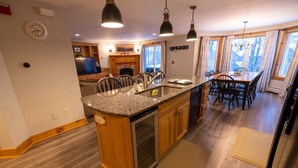 Eine Küche mit Granit-Arbeitsplatten, Holzschränken, einem eingebauten Backofen und Pendelleuchten.