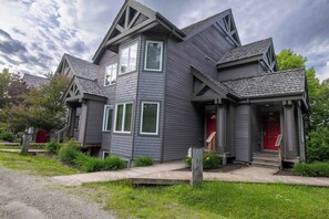 A two-story house with a red door, a front porch, and a well-maintained garden.