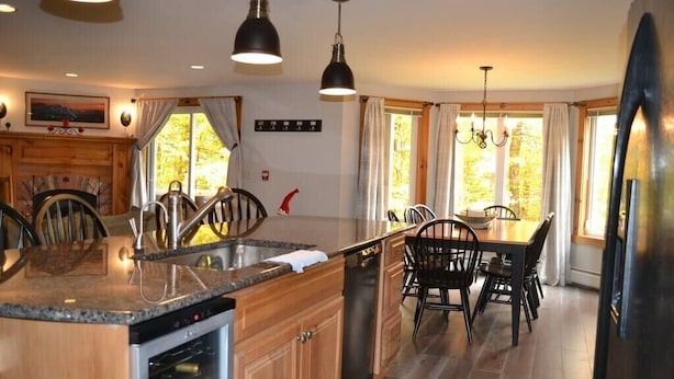 A modern kitchen with granite countertops, wooden cabinets, and a dining area with a wooden table and chairs.