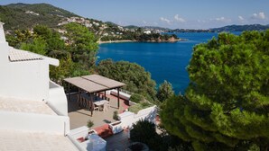 A coastal property with a patio overlooking the sea, a white building, and surrounding greenery. - Daphne By Luxury Villas Skiathos (Skiathos)