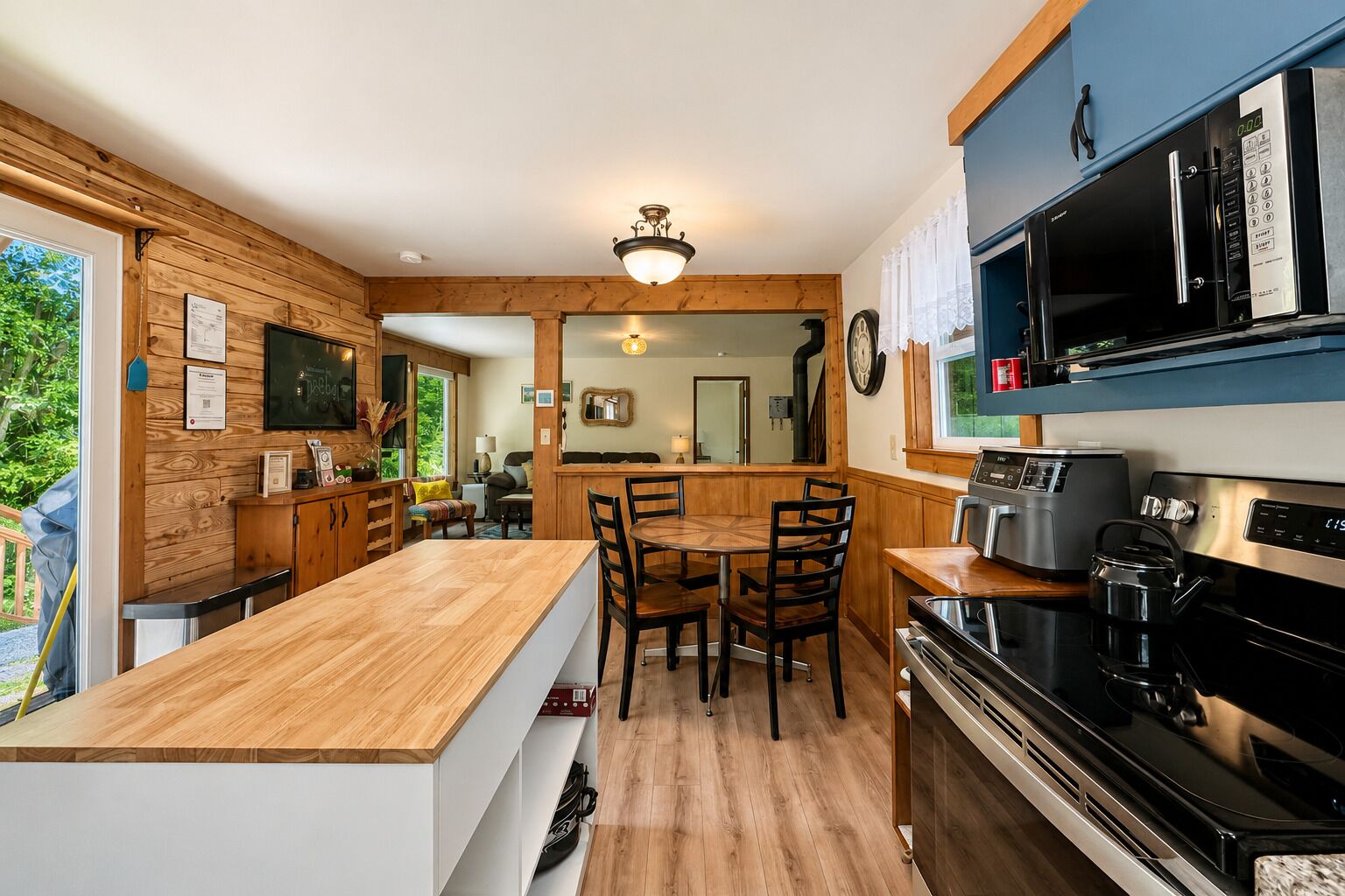 A kitchen with wooden cabinetry, a dining area with chairs, a large stove, and a microwave.