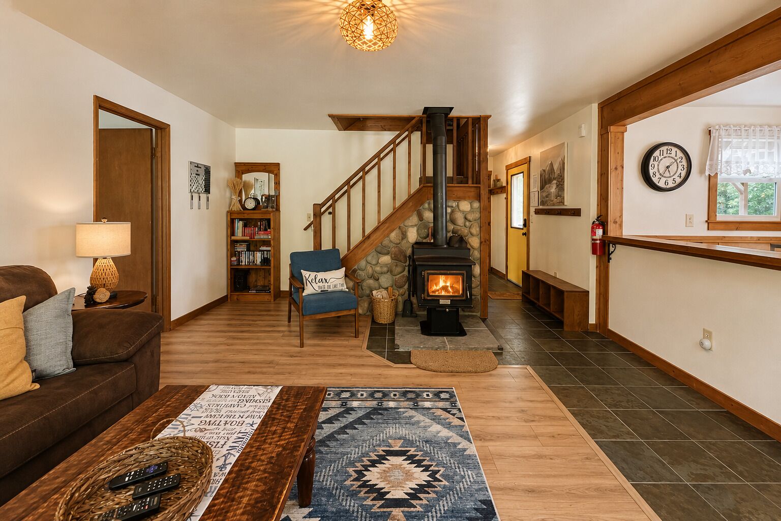 A cozy living room with a fireplace, a staircase, a bookshelf, and a couch.