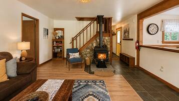 A cozy living room with a fireplace, a staircase, a bookshelf, and a couch.