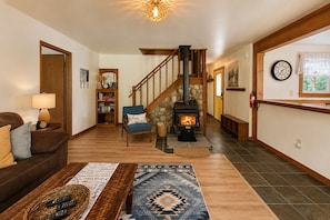 A cozy living room with a fireplace, a staircase, a bookshelf, and a couch.