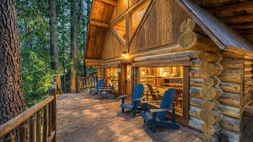 A log cabin with a deck, chairs, and a dining area.
