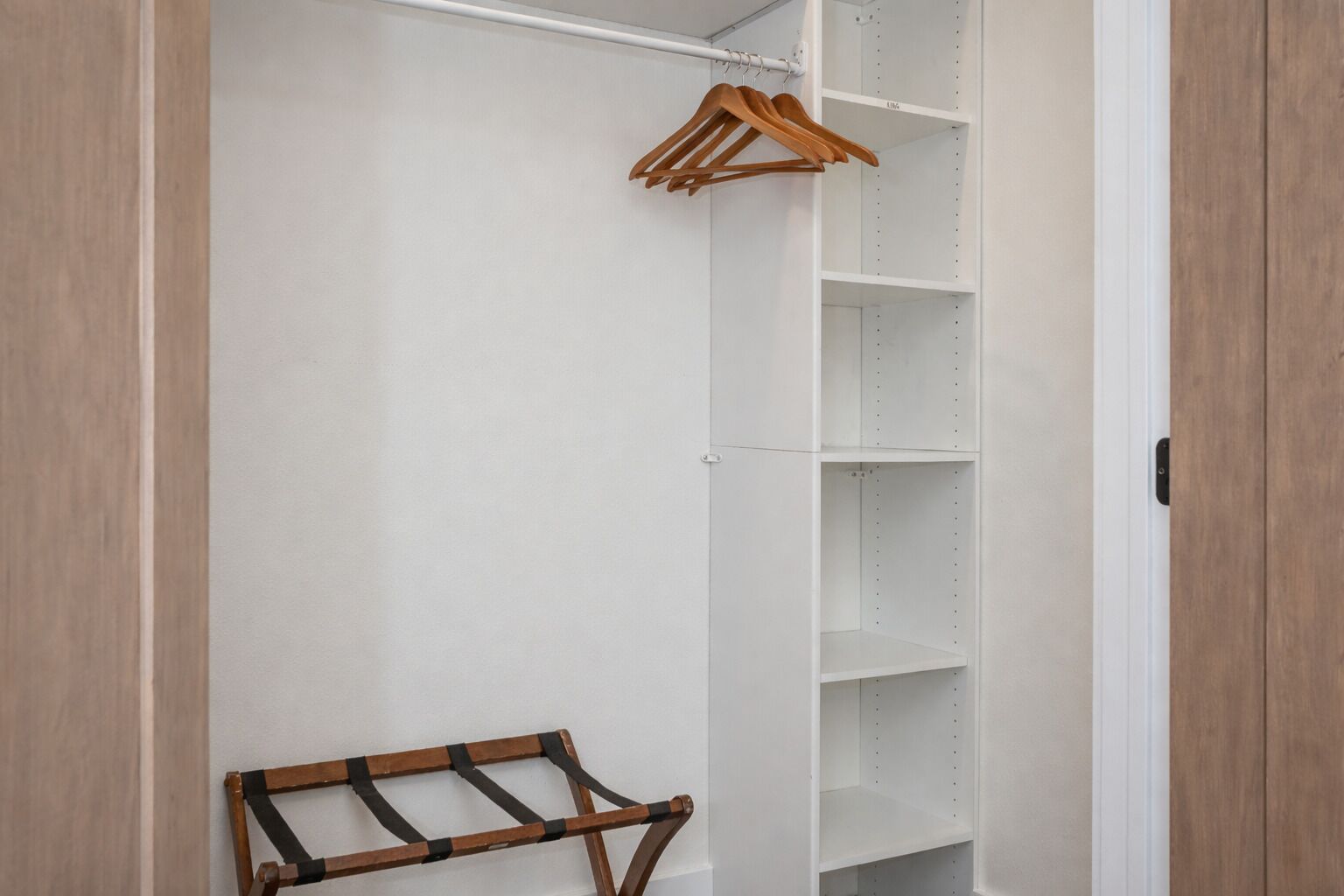 A walk-in closet with open shelves and a wooden drying rack.