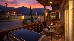 A patio with a grill, wicker chairs, and a table with wine glasses and bottles. - Bavarian Mountain Suite 2 Bedroom Condo by NW Comfy Cabins by RedAwning (Leavenworth)