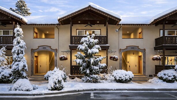 A multi-story hotel with a snow-covered exterior, a central balcony, and a staircase leading to the entrance. - Bavarian Mountain Suite 2 Bedroom Condo by NW Comfy Cabins by RedAwning (Leavenworth)