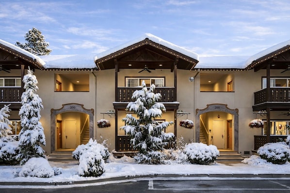 A multi-story hotel with a snow-covered exterior, a central balcony, and a staircase leading to the entrance. - Bavarian Mountain Suite 2 Bedroom Condo by NW Comfy Cabins by RedAwning (Leavenworth)