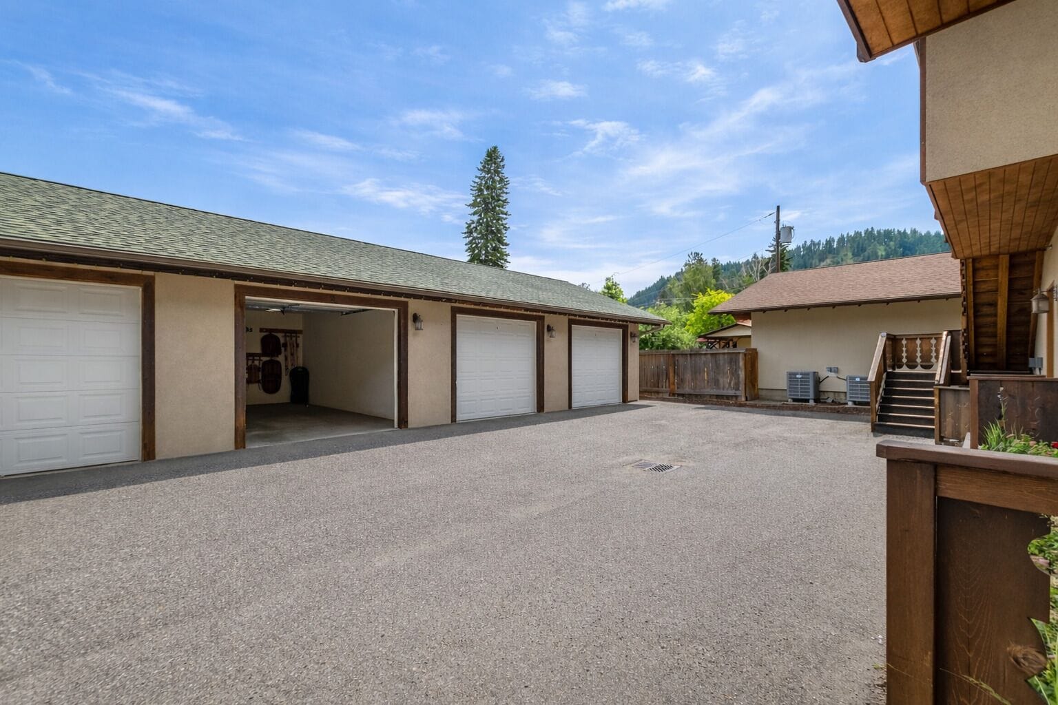 A building with multiple garage doors, a gravel driveway, and a wooden fence.