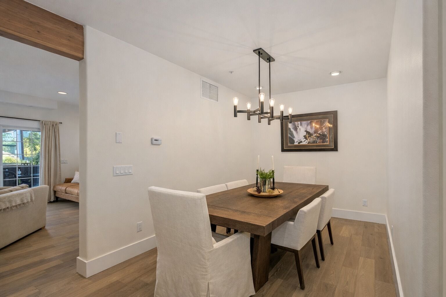 A dining area with a wooden table, white chairs, and a pendant light.